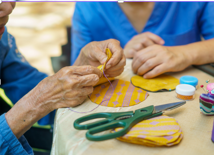 caregiver assisting memory care patient at home with holiday crafts